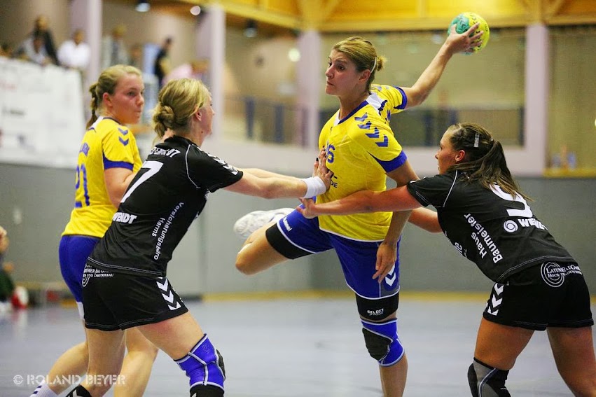 Eine Handballerin wird von zwei Gegenspielerinnen am Wurf gehindert
